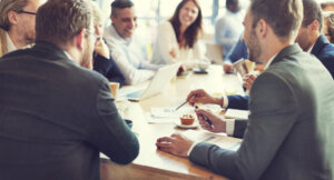 Um grupo de profissionais corporativos sorri e fala em uma reunião