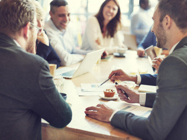 Um grupo de profissionais corporativos sorri e conversa em uma reunião Imagem