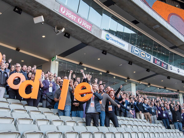 People in stadium at Moodle Moot holding 'Moodle' letters Image
